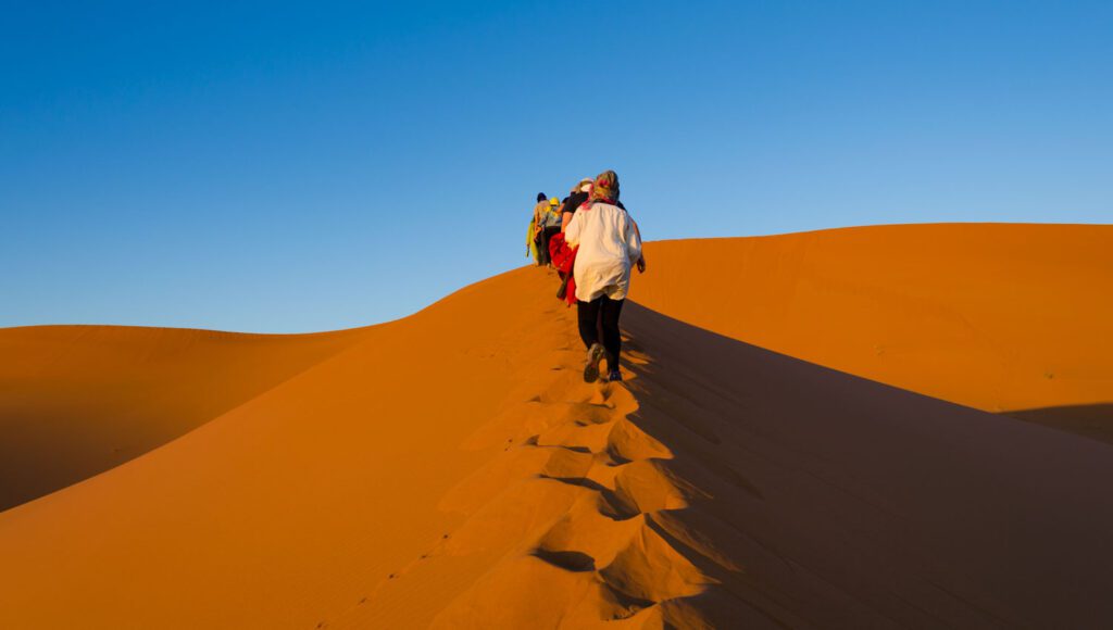 image of people walking in the Sahara desert Morocco